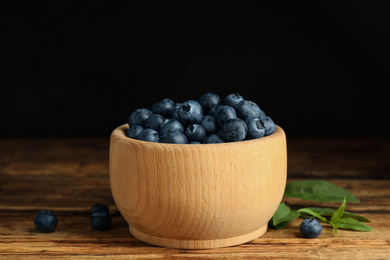 Photo of Fresh ripe blueberries in bowl on wooden table