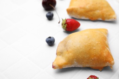 Photo of Delicious samosas and berries on white tiled table, closeup. Space for text