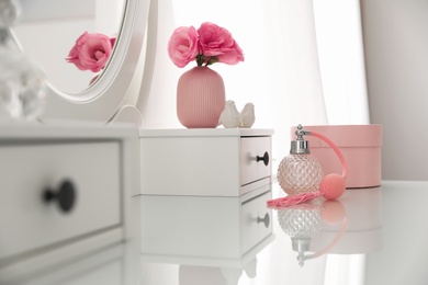 Photo of White dressing table with decor and bottle of perfume in room
