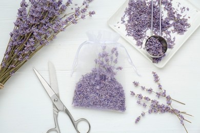 Photo of Scented sachet with dried lavender flowers and scissors on white wooden table, flat lay