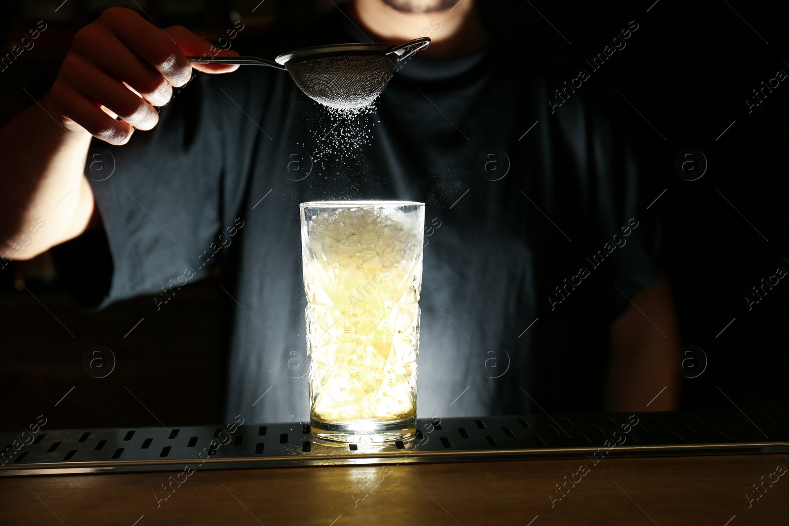 Photo of Bartender decorating glass of fresh alcoholic cocktail at bar counter, closeup