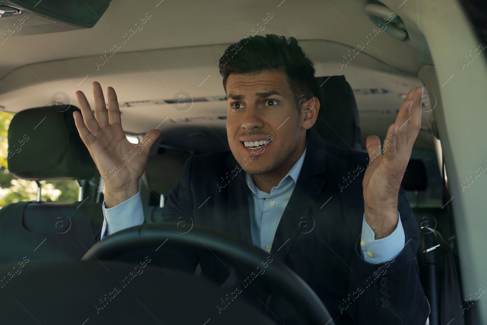 Photo of Stressed angry man in driver's seat of modern car, view through windshield