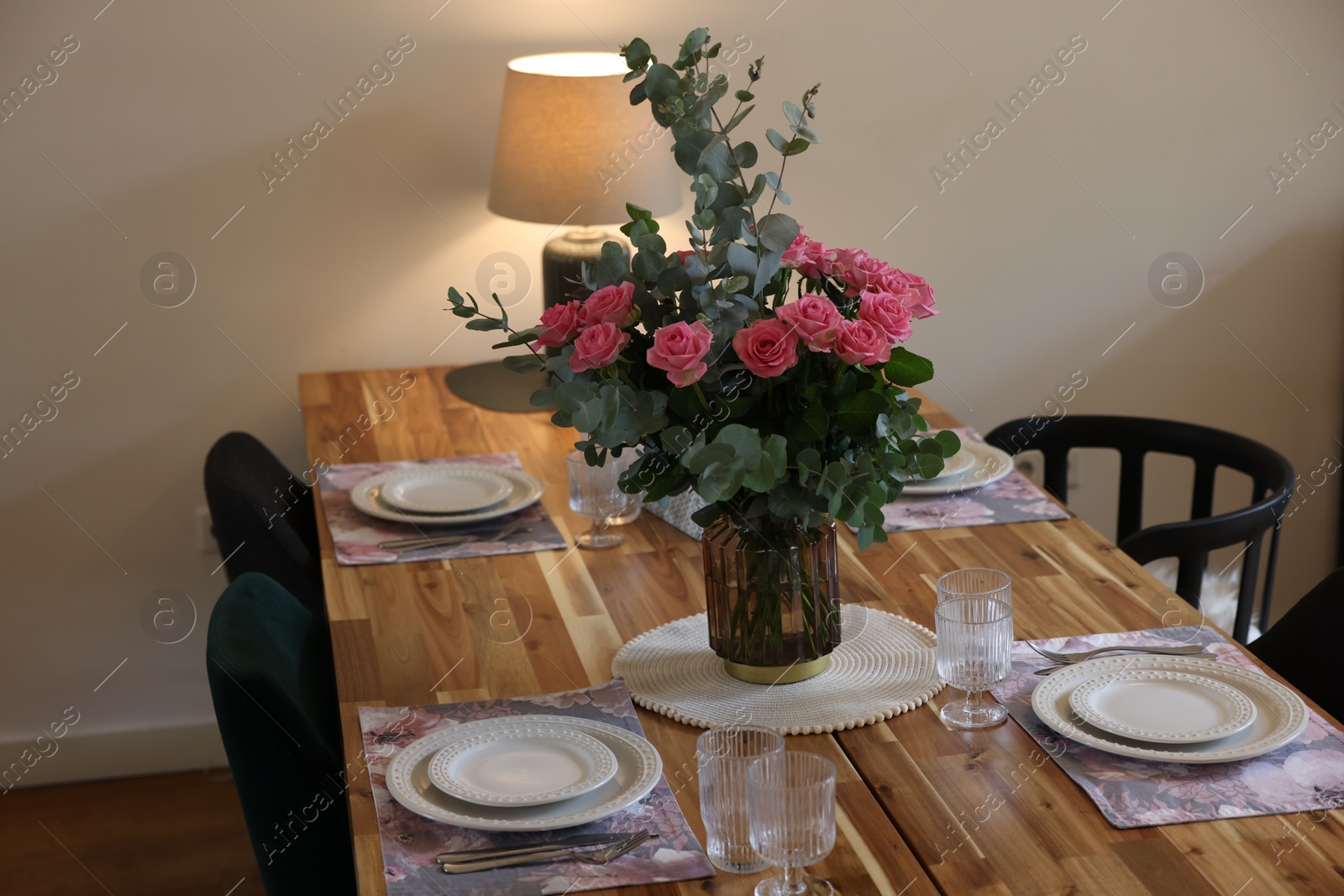 Photo of Beautiful table setting with bouquet indoors. Roses and eucalyptus branches in vase