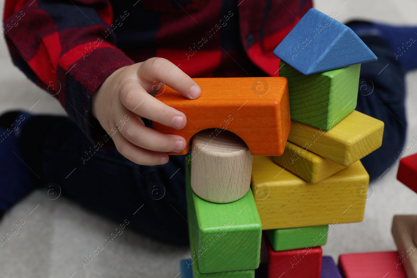 Photo of Little child playing with building blocks on carpet, closeup