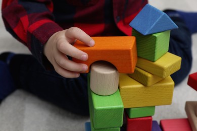 Photo of Little child playing with building blocks on carpet, closeup