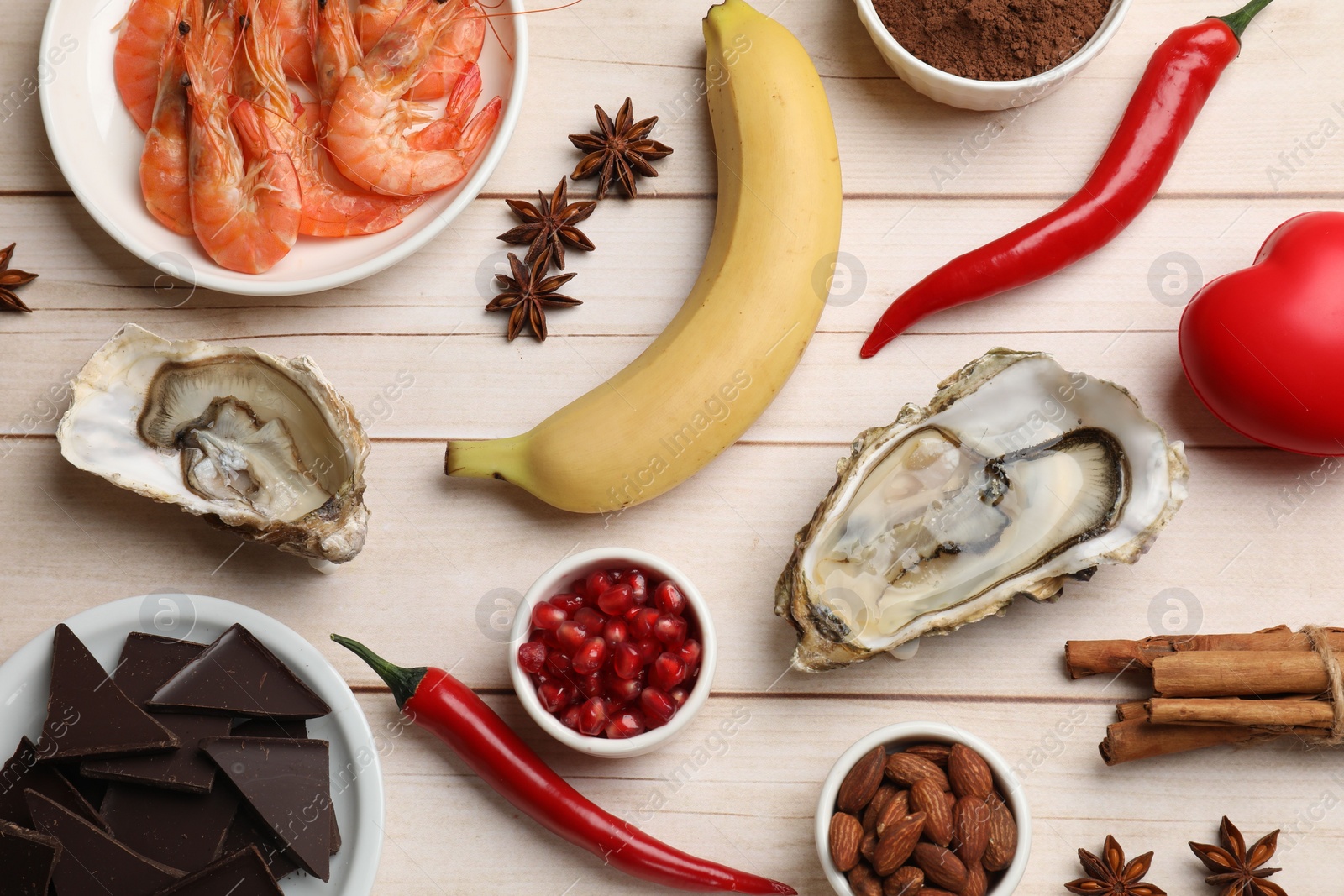 Photo of Natural aphrodisiac. Different food products and red decorative heart on light wooden table, flat lay