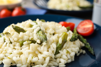 Photo of Delicious risotto with asparagus in plate, closeup