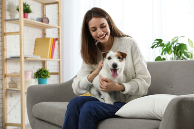 Young woman with her cute Jack Russell Terrier on sofa at home. Lovely pet