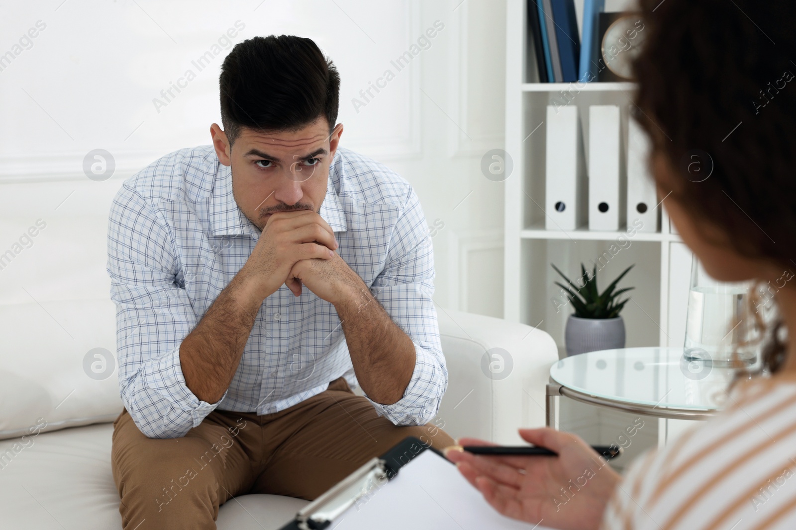 Photo of Unhappy man having session with his therapist indoors