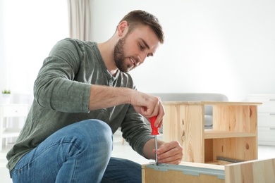 Young working man repairing drawer at home