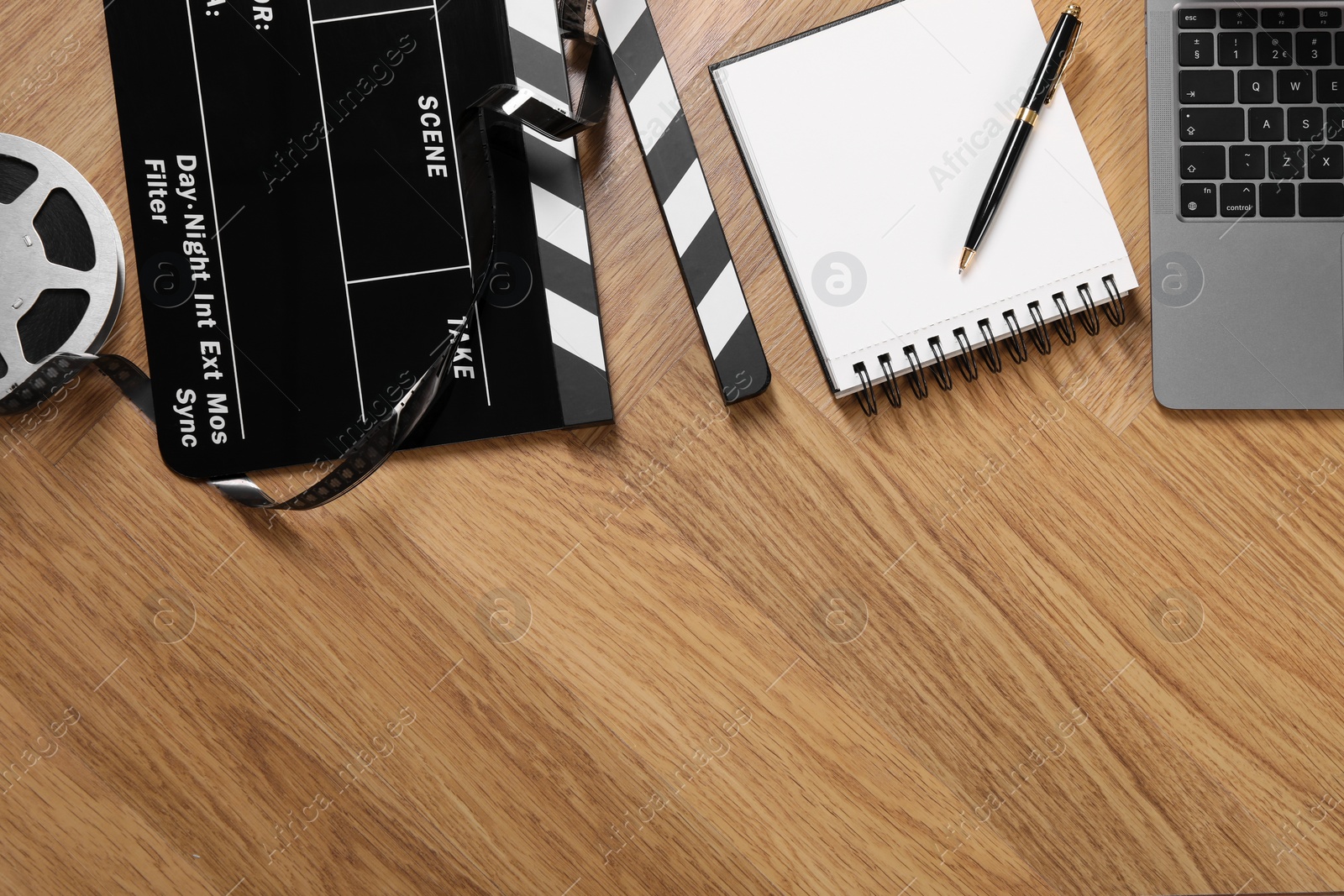 Photo of Movie clapper, film reel, notebook and laptop on wooden table, flat lay. Space for text