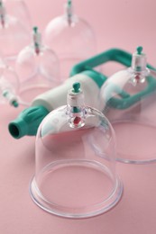 Photo of Plastic cups and hand pump on pink background, closeup. Cupping therapy