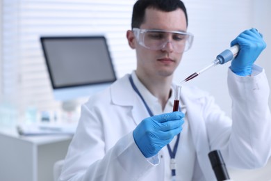 Photo of Scientist dripping sample into test tube in laboratory, selective focus