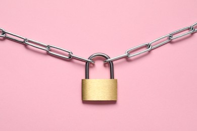 Photo of Steel padlock with chain on pink background, top view