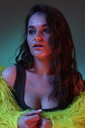 Photo of Portrait of beautiful woman in yellow fur coat on dark background with neon lights