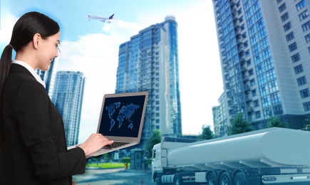 Image of Logistics concept. Businesswoman using laptop with world map. Truck, plane and buildings on background, toned in blue