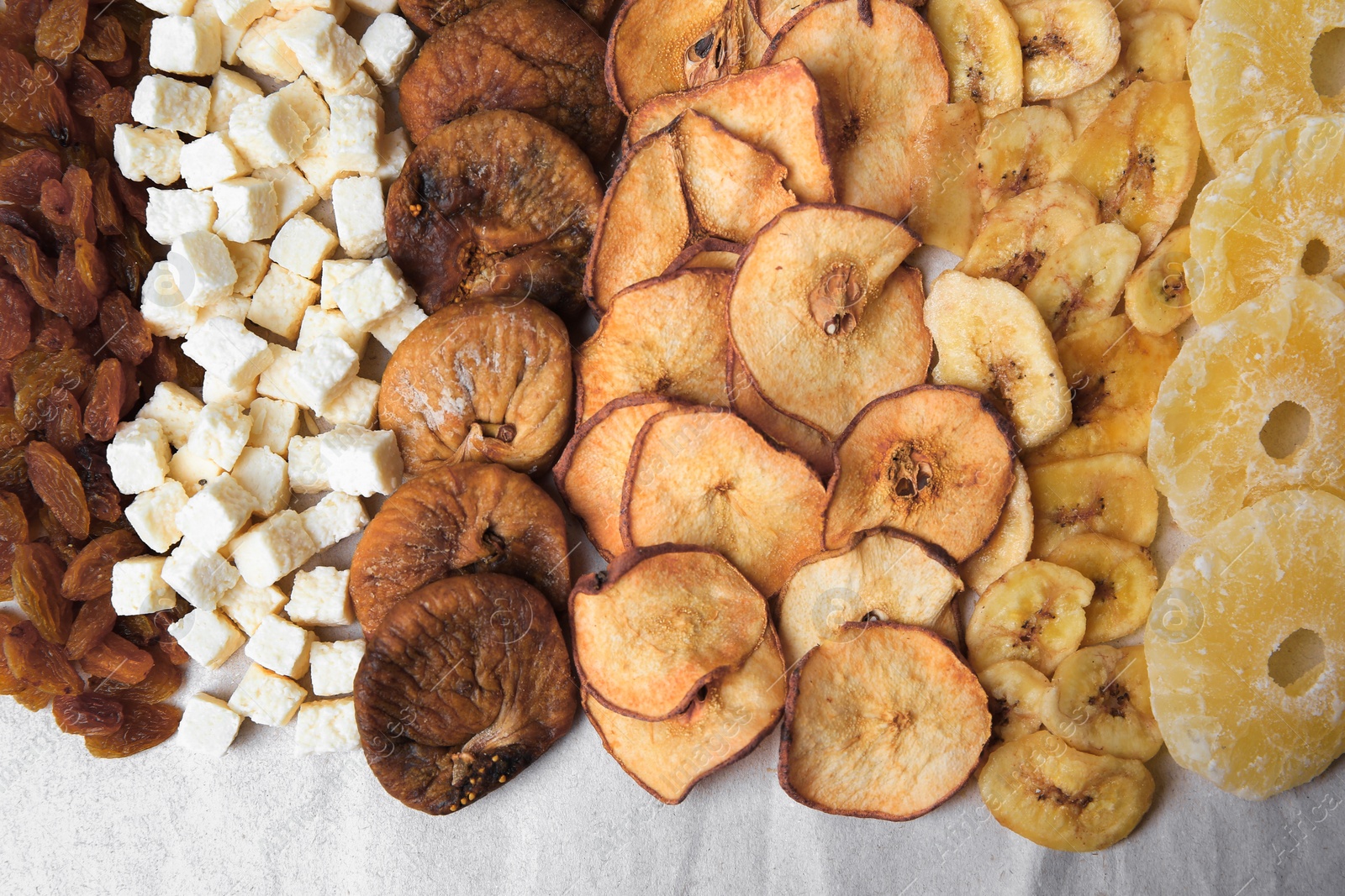 Photo of Different tasty dried fruits on paper, flat lay