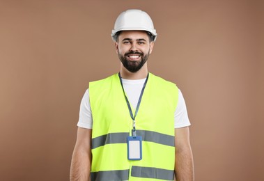 Photo of Engineer with hard hat and badge on brown background
