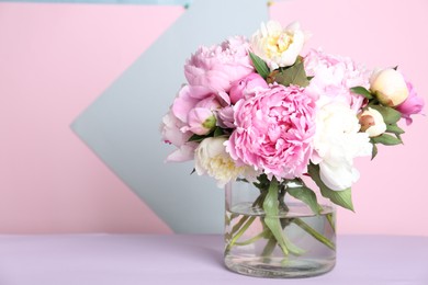 Photo of Bouquet of beautiful peonies in vase on lilac table. Space for text