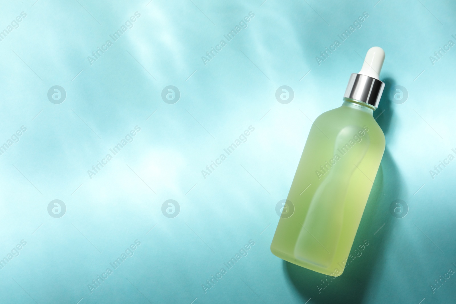 Photo of Bottle of hydrophilic oil on light blue background, top view. Space for text