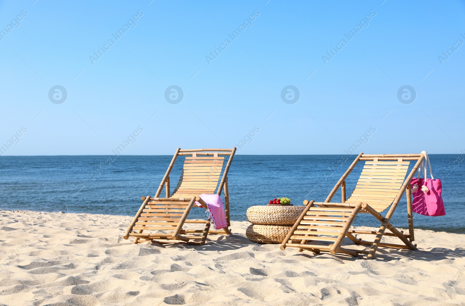 Photo of Empty wooden sunbeds and beach accessories on sandy shore