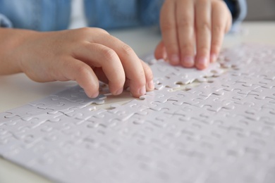 Photo of Little girl playing with puzzles at table, closeup