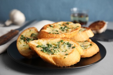 Plate with delicious homemade garlic bread on table