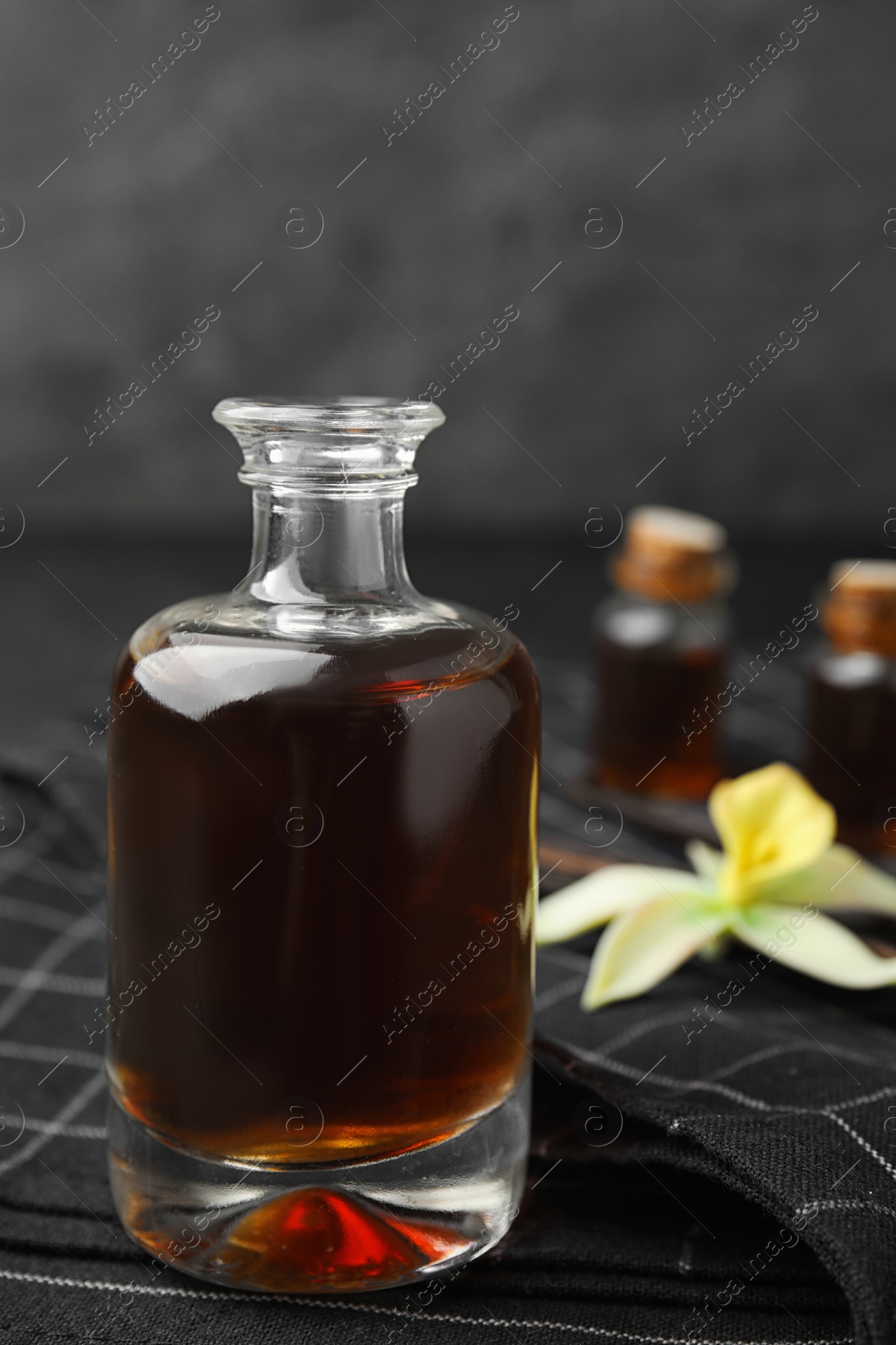 Photo of Aromatic homemade vanilla extract in glass bottle on table, closeup