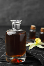 Aromatic homemade vanilla extract in glass bottle on table, closeup