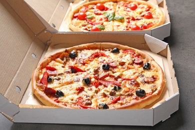 Photo of Cardboard box with delicious pizza on table