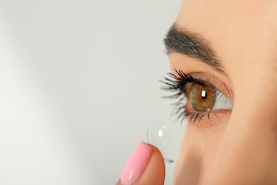 Photo of Young woman putting contact lens in her eye, closeup. Space for text