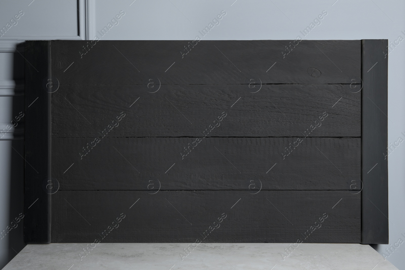 Photo of Wooden board on table near light grey wall