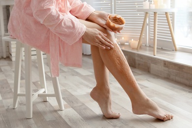 Photo of Young woman applying natural scrub onto her skin in bathroom