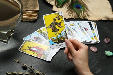 Photo of Woman with tarot cards at black table, closeup