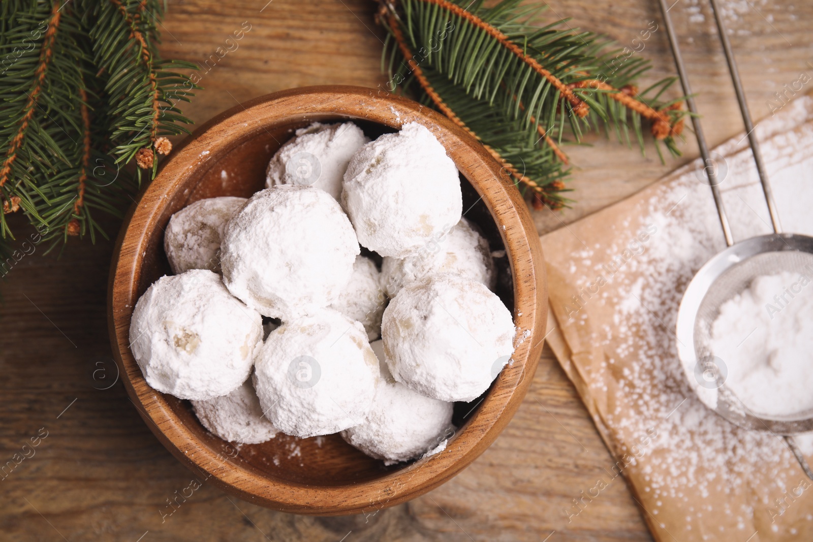 Photo of Tasty Christmas snowball cookies in bowl on wooden table, flat lay