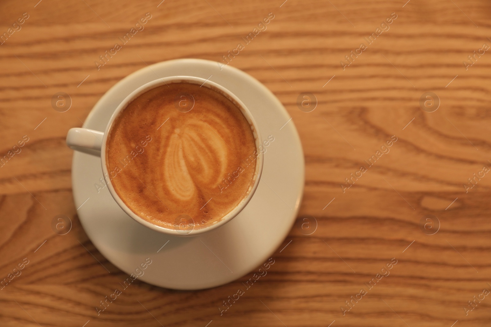 Photo of Cup of hot coffee on wooden table, top view. Space for text