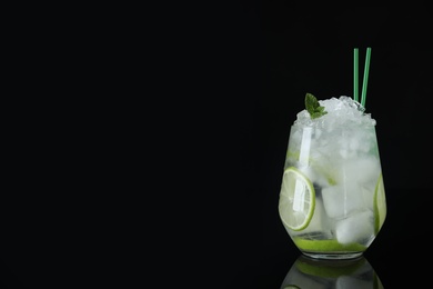 Photo of Glass of cocktail with vodka, ice and lime on black background. Space for text