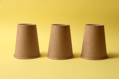Photo of Three paper cups on yellow background. Thimblerig game