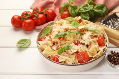 Photo of Plate of delicious pasta with tomatoes, basil and parmesan cheese on white wooden table