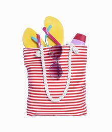 Photo of Beach bag with sunglasses, sunscreen and flip flops isolated on white