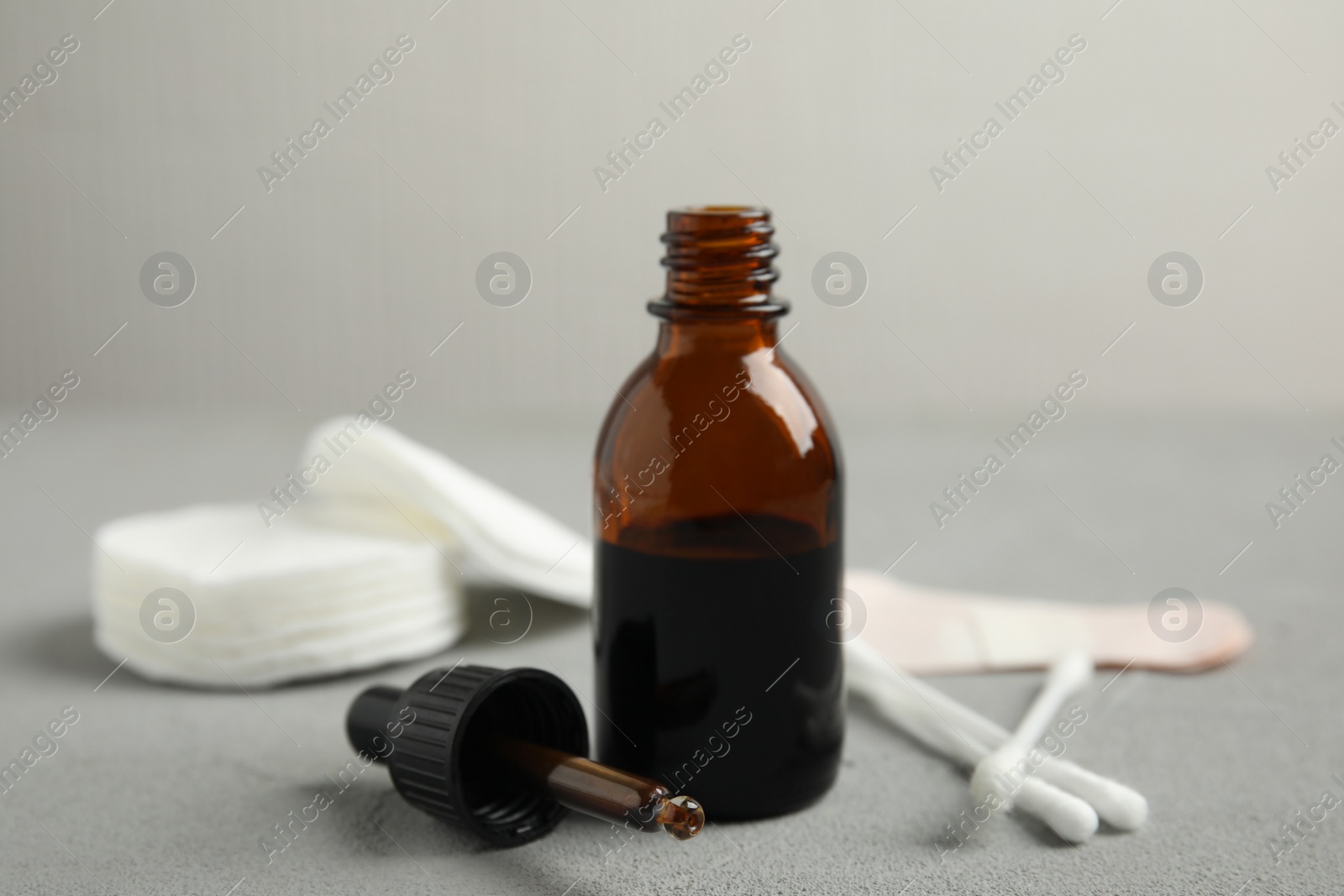 Photo of Bottle of medical iodine, dropper and cotton buds on grey table