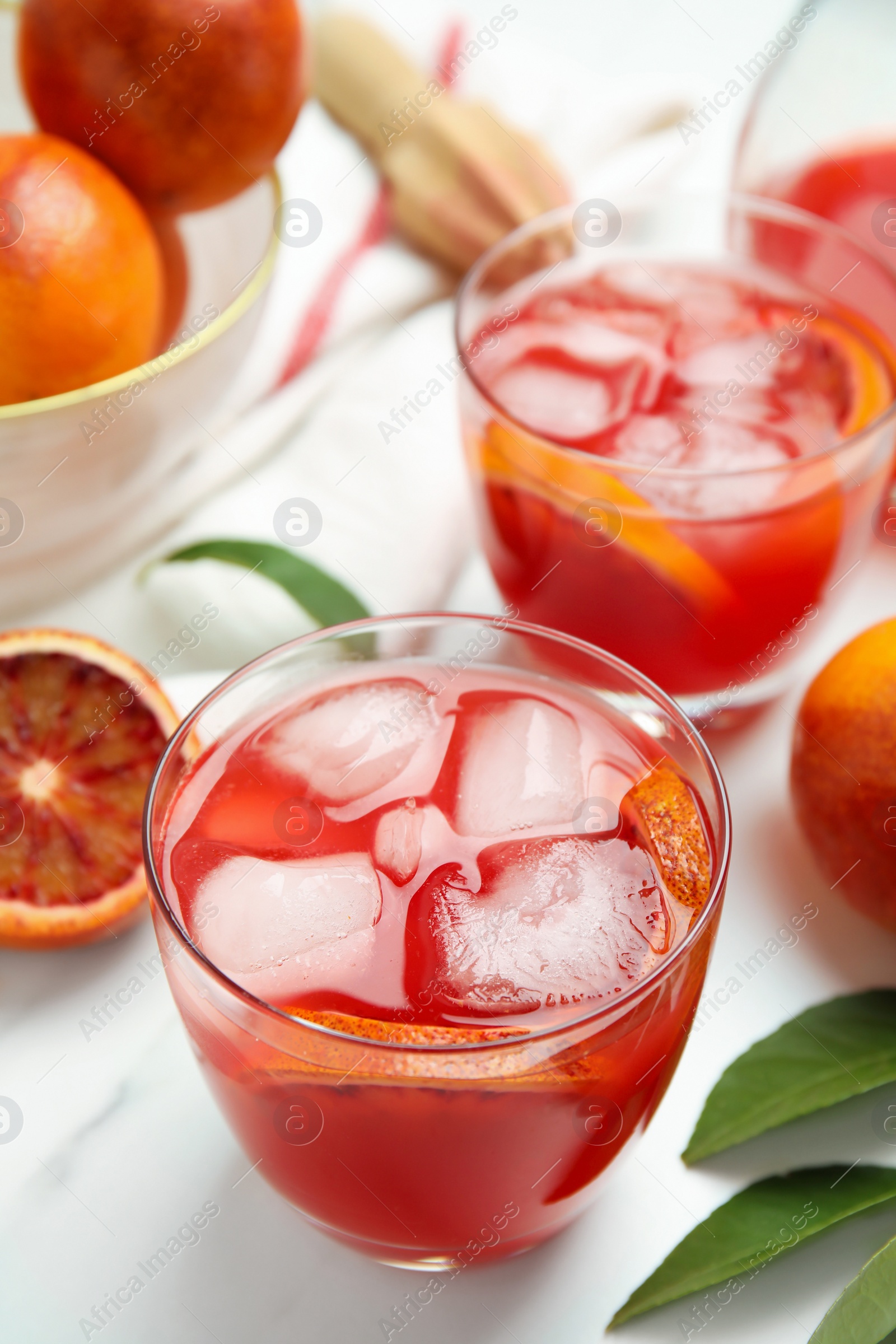 Photo of Tasty sicilian orange juice with ice cubes and fruits on white marble table