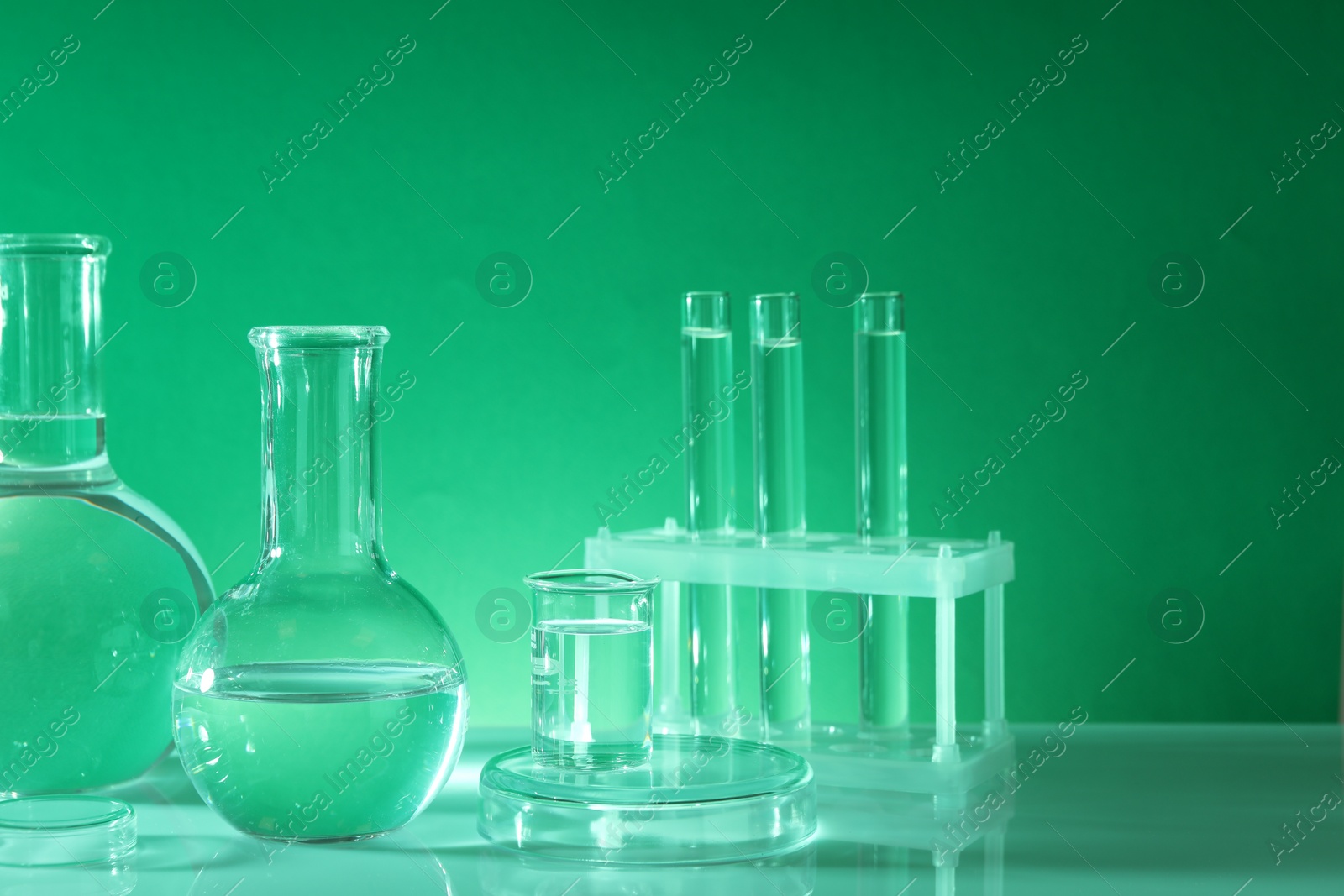 Photo of Laboratory analysis. Different glassware on table against green background