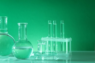 Laboratory analysis. Different glassware on table against green background