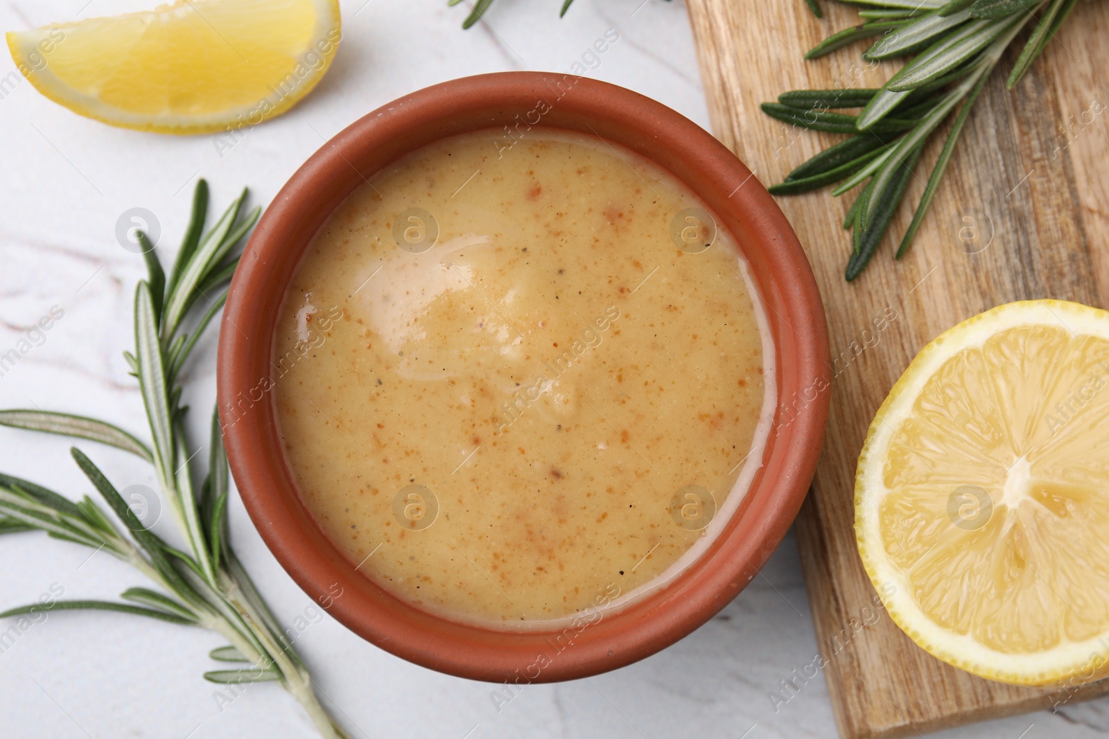 Photo of Delicious turkey gravy, rosemary and lemon on white table, flat lay