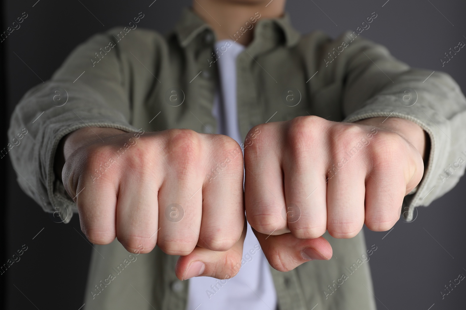 Photo of Man showing fists with space for tattoo on grey background, closeup