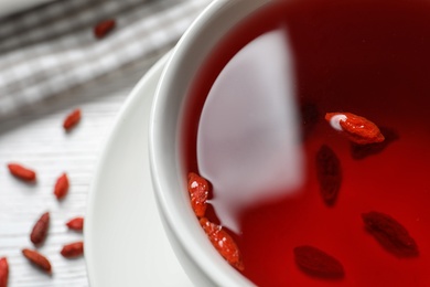 Photo of Healthy goji tea in cup on white table, closeup