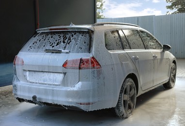 Auto with cleaning foam at outdoor car wash