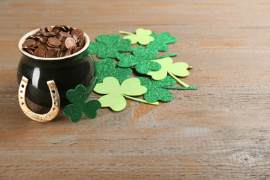 Pot of gold coins, horseshoe and clover leaves on wooden table. St. Patrick's Day celebration