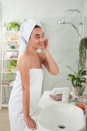 Photo of Beautiful young woman in bathroom. Facial wash